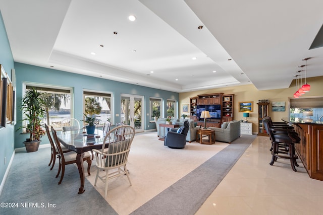 dining area featuring light tile patterned floors and a raised ceiling