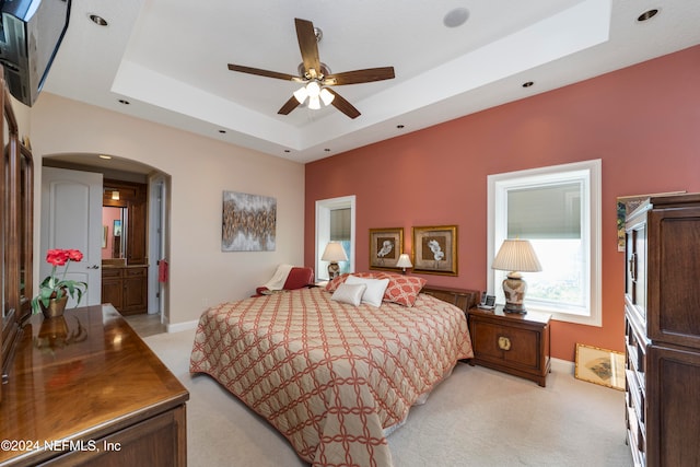 carpeted bedroom featuring ceiling fan and a raised ceiling