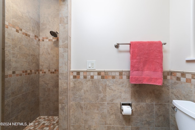 bathroom with toilet, tile walls, and tiled shower