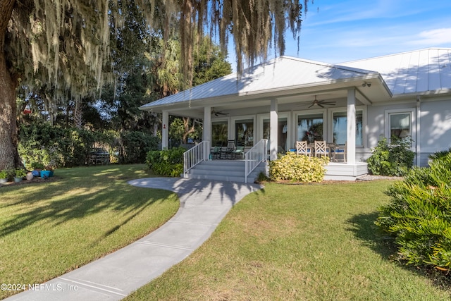 rear view of property featuring covered porch, ceiling fan, and a yard