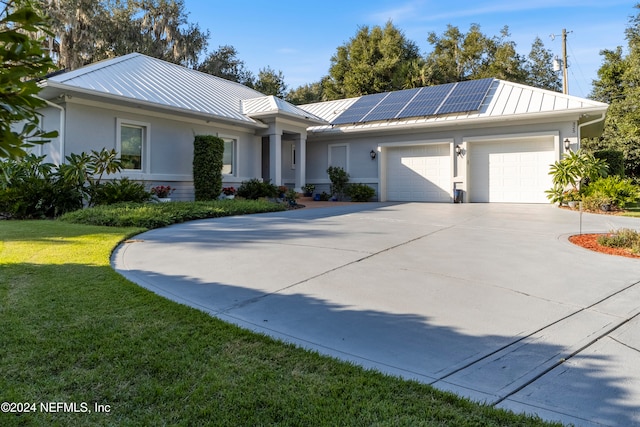 single story home featuring solar panels, a front lawn, and a garage