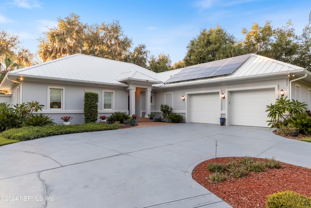 ranch-style home featuring solar panels and a garage