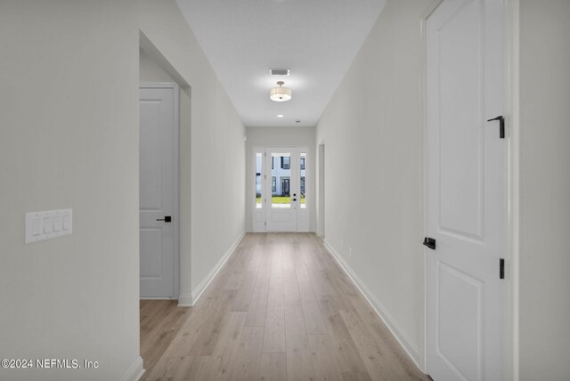 hall featuring light hardwood / wood-style flooring and french doors