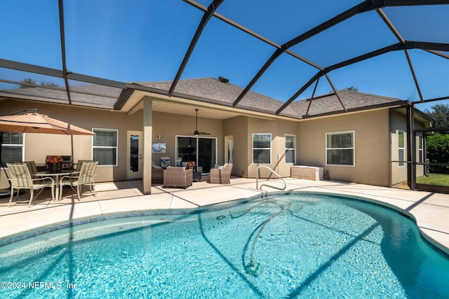 view of pool featuring glass enclosure, ceiling fan, and a patio