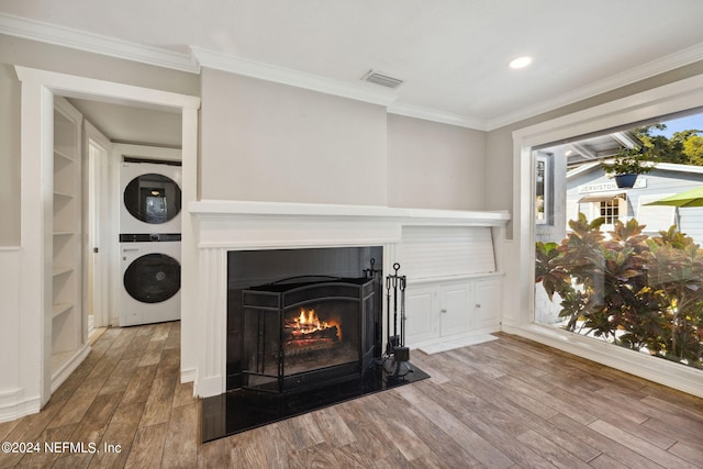 interior space with crown molding, stacked washer / drying machine, and wood-type flooring