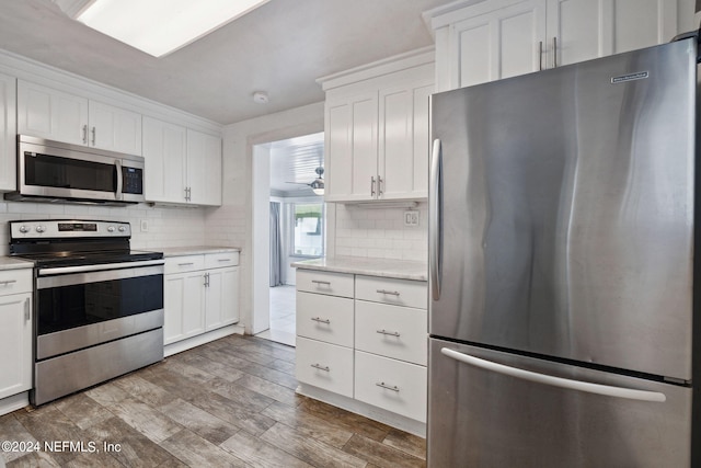 kitchen with tasteful backsplash, appliances with stainless steel finishes, light hardwood / wood-style flooring, and white cabinets