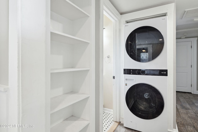 laundry room featuring stacked washing maching and dryer, built in features, and light wood-type flooring