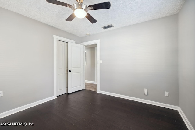 empty room featuring ceiling fan, dark hardwood / wood-style floors, and a textured ceiling