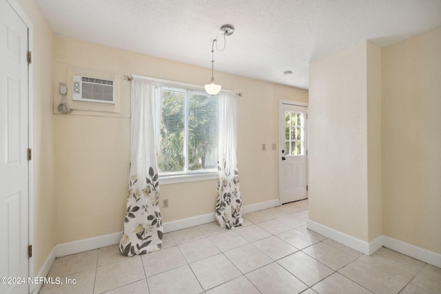 unfurnished dining area with an AC wall unit, light tile patterned floors, and a textured ceiling