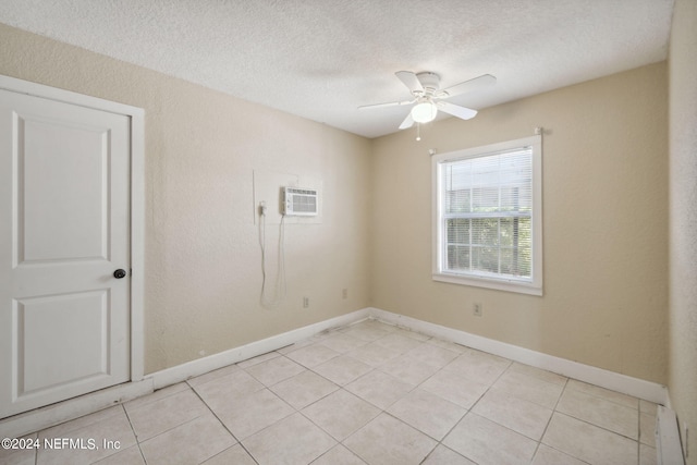 tiled empty room featuring ceiling fan, a wall mounted AC, and a textured ceiling