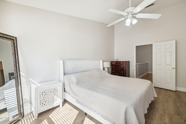 bedroom featuring ceiling fan, hardwood / wood-style floors, and a high ceiling