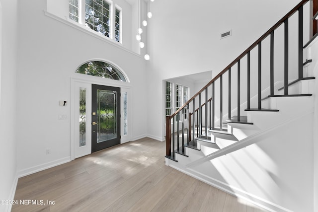 foyer entrance with light hardwood / wood-style floors and a towering ceiling