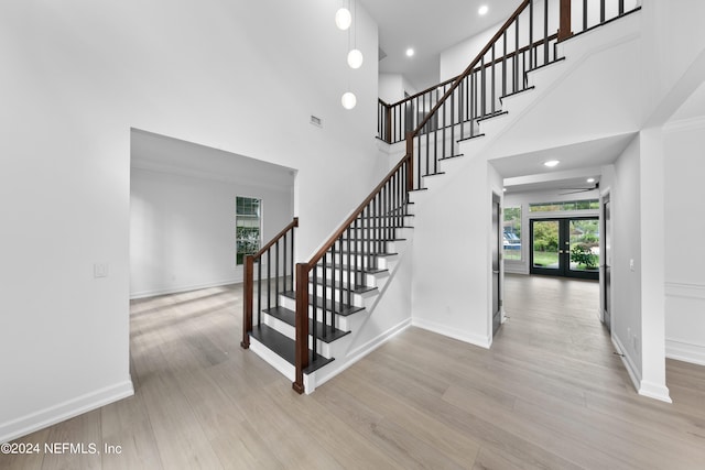 stairway with hardwood / wood-style floors, french doors, and a towering ceiling