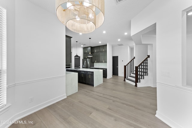 kitchen with decorative backsplash, light hardwood / wood-style flooring, stainless steel fridge, a center island, and pendant lighting