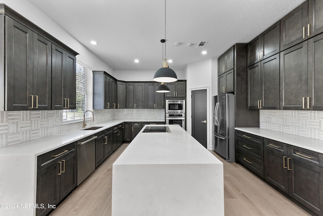 kitchen featuring a kitchen island, light wood-type flooring, stainless steel appliances, pendant lighting, and sink