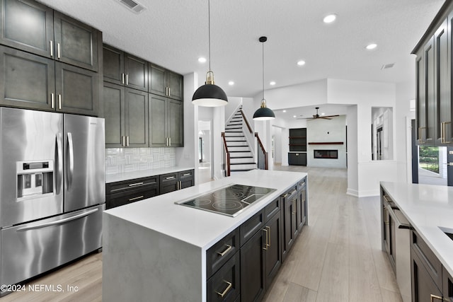 kitchen with black electric stovetop, a center island, light hardwood / wood-style floors, pendant lighting, and stainless steel refrigerator with ice dispenser