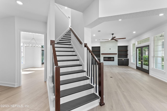 stairway with french doors, a textured ceiling, ceiling fan with notable chandelier, and hardwood / wood-style floors