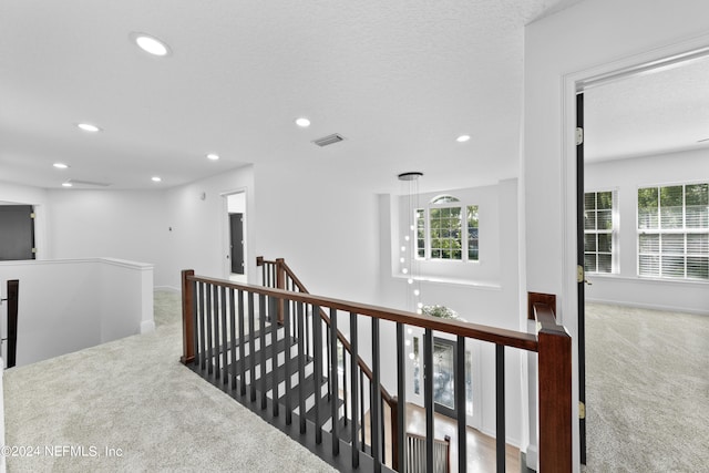 corridor with a textured ceiling and carpet floors