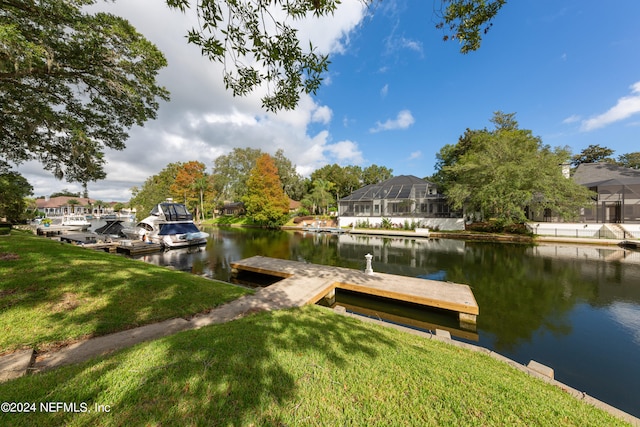 view of dock featuring a water view, a lawn, and glass enclosure