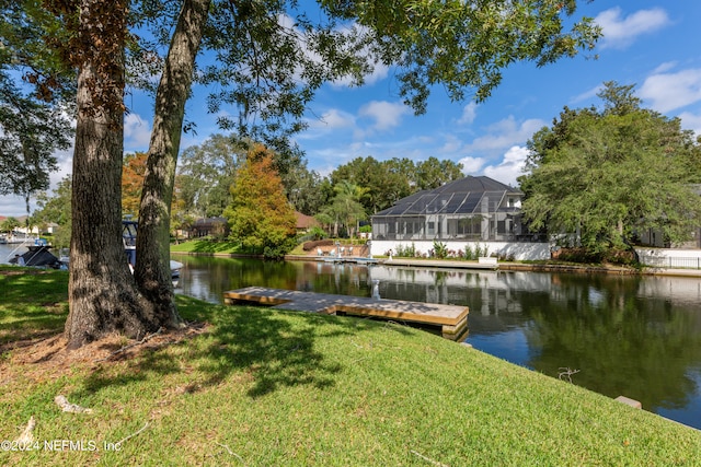 view of dock featuring a water view, a lawn, and a lanai