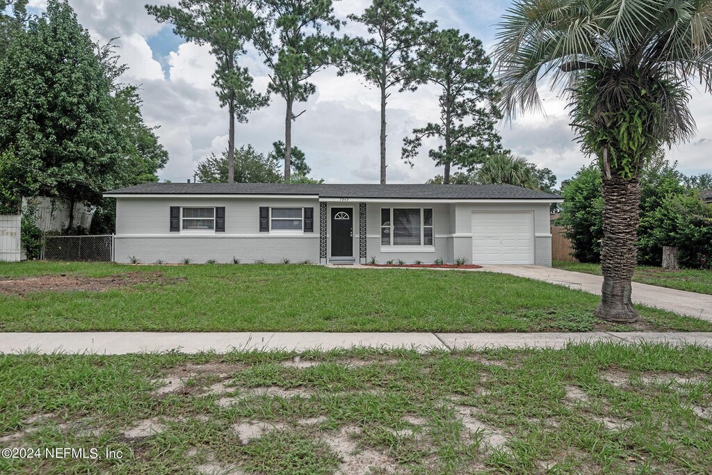 single story home featuring a garage and a front lawn