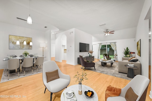 living room featuring arched walkways, visible vents, ceiling fan, and wood finished floors