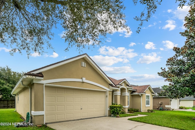 view of front of home with a garage, concrete driveway, stucco siding, and a front lawn