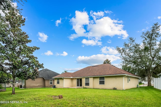 back of property featuring central air condition unit and a yard