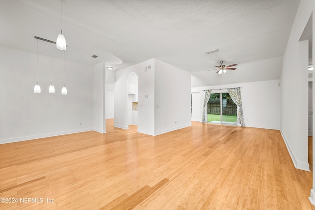 unfurnished living room with ceiling fan, a textured ceiling, and light hardwood / wood-style flooring