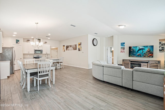 dining room with vaulted ceiling, sink, light hardwood / wood-style flooring, and a notable chandelier