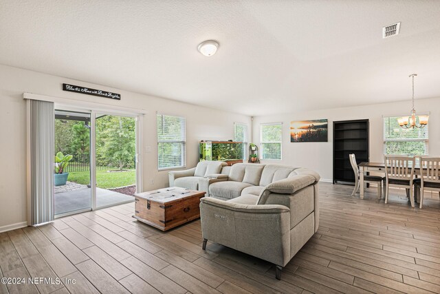 living room featuring light wood-type flooring, a textured ceiling, and a chandelier