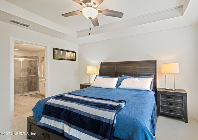 bedroom featuring light hardwood / wood-style flooring, ensuite bath, and ceiling fan