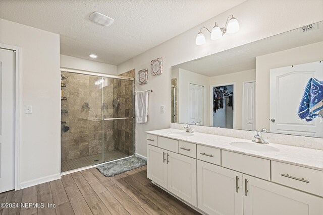 bathroom featuring wood-type flooring, a textured ceiling, a shower with door, and vanity