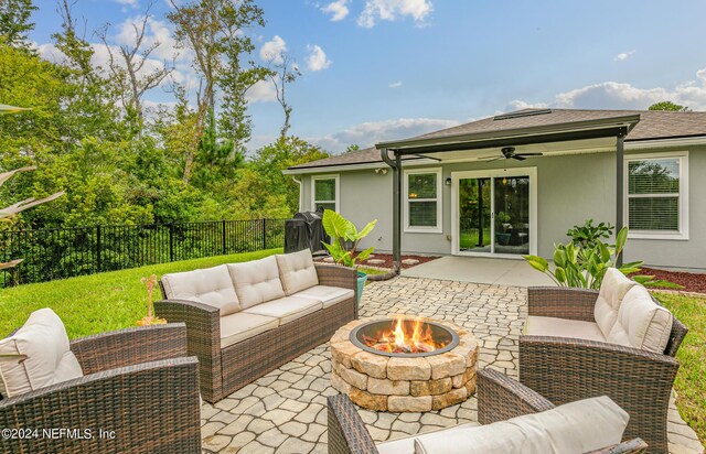 view of patio / terrace with ceiling fan and an outdoor living space with a fire pit