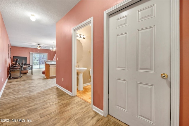 hall with a textured ceiling and light hardwood / wood-style floors