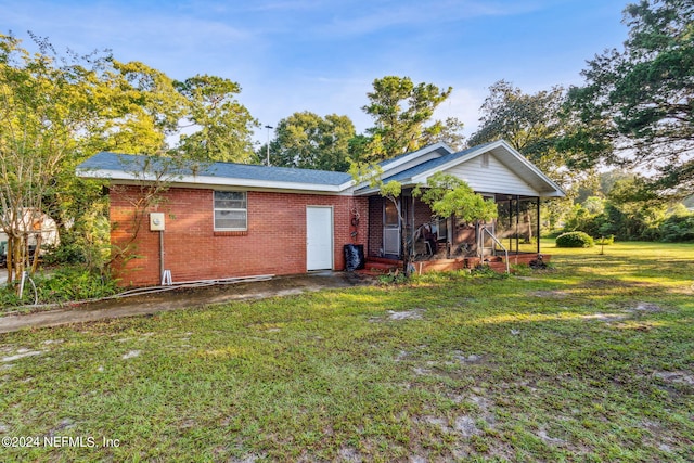 back of property with a yard and a sunroom