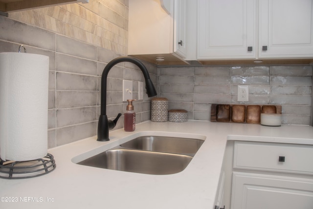 details featuring white cabinetry, sink, and backsplash