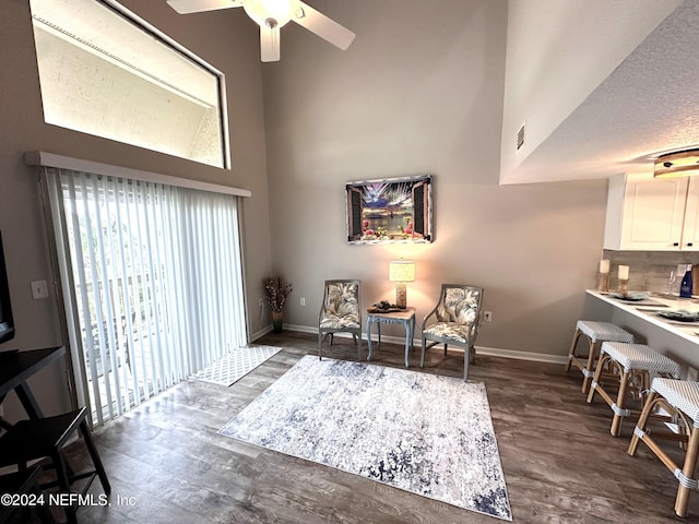 living area featuring ceiling fan, a towering ceiling, and dark hardwood / wood-style flooring