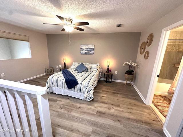 bedroom featuring hardwood / wood-style flooring, a textured ceiling, ceiling fan, and ensuite bathroom