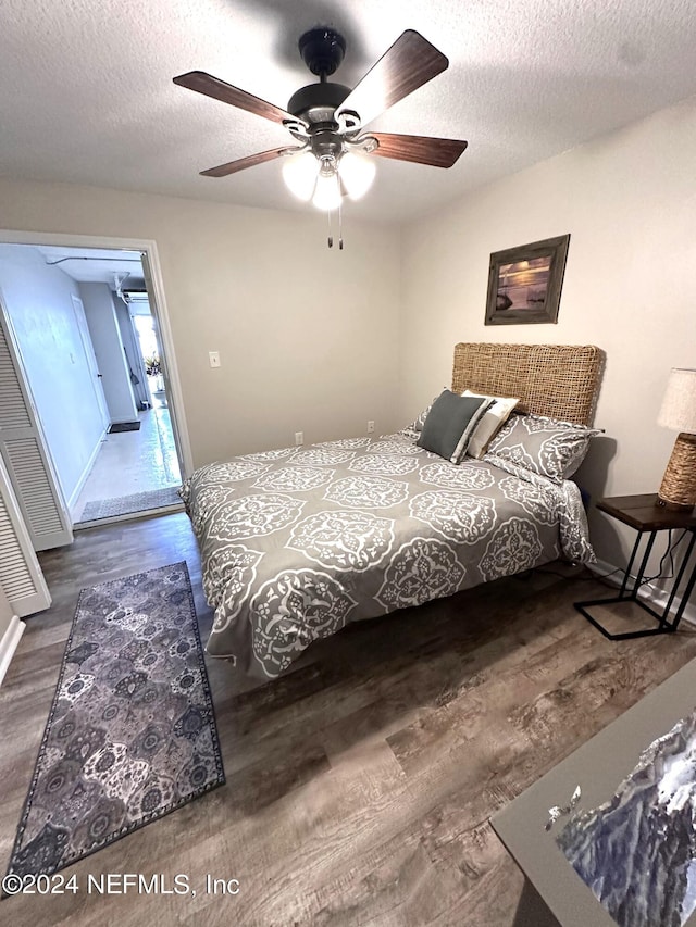 bedroom featuring ceiling fan, dark wood-type flooring, and a textured ceiling