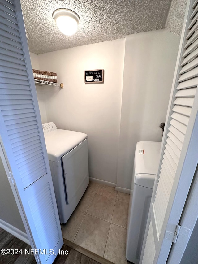 laundry area featuring a textured ceiling, tile patterned floors, and independent washer and dryer