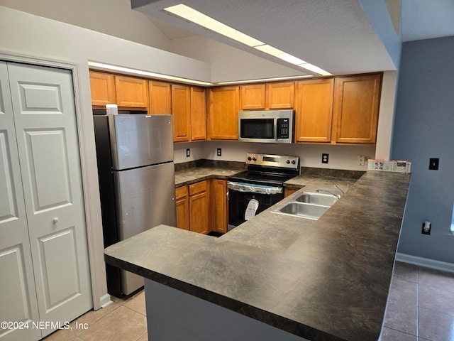 kitchen with light tile patterned floors, sink, kitchen peninsula, appliances with stainless steel finishes, and vaulted ceiling