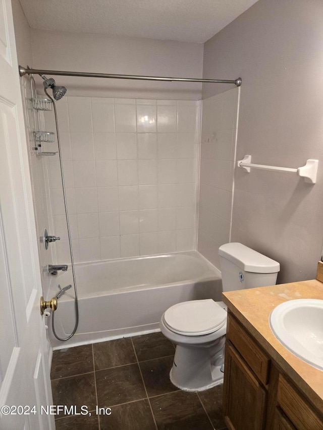 full bathroom featuring tiled shower / bath, vanity, a textured ceiling, toilet, and tile patterned floors