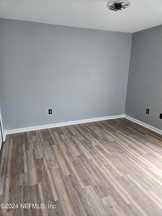 unfurnished room featuring a textured ceiling and light hardwood / wood-style flooring