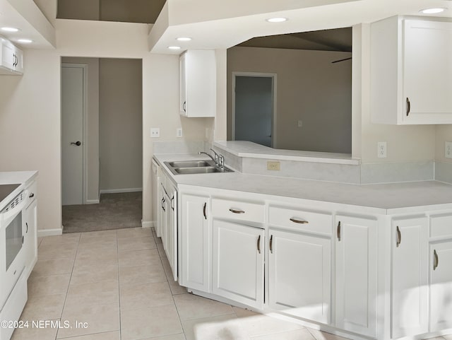 kitchen with white cabinets, light tile patterned flooring, sink, and white stove