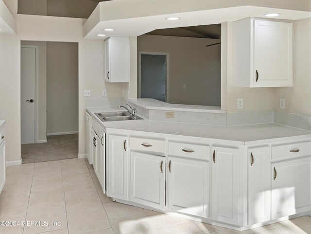 kitchen with light tile patterned floors, sink, and white cabinetry