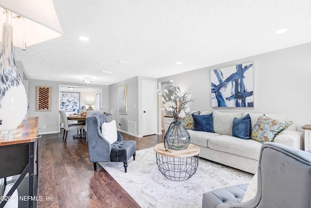 living room with a textured ceiling and dark hardwood / wood-style floors