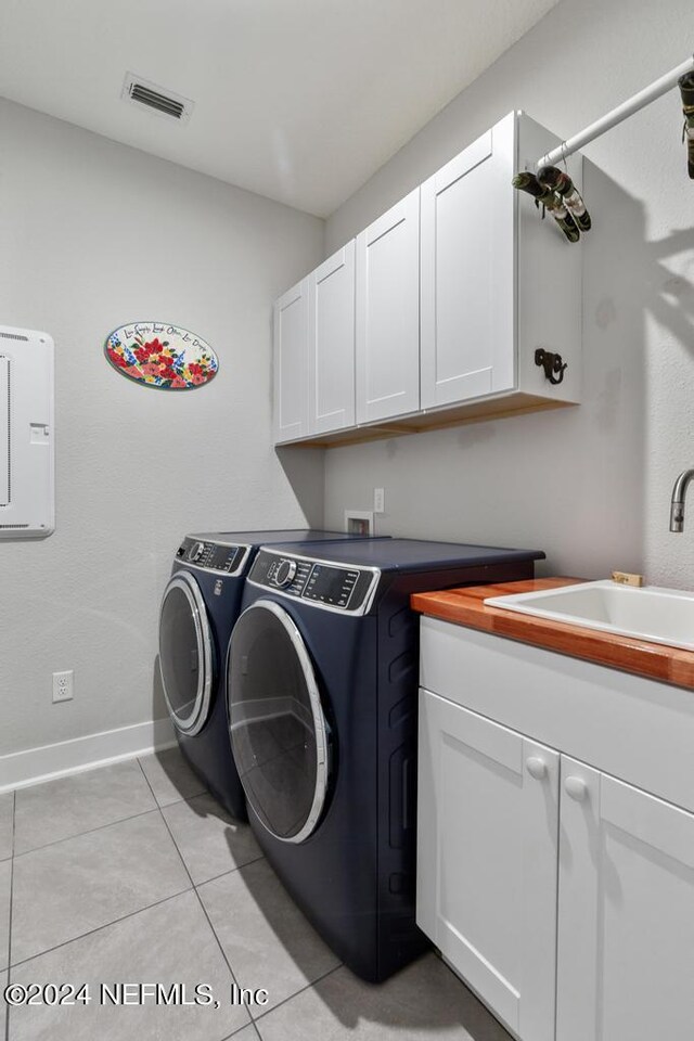 washroom with washer and clothes dryer, light tile patterned flooring, sink, and cabinets