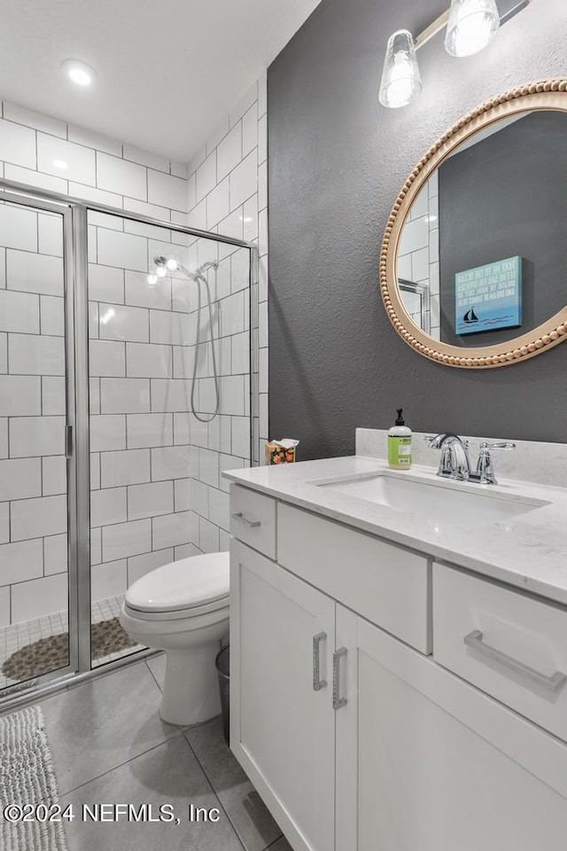 bathroom with tile patterned flooring, an enclosed shower, vanity, and toilet