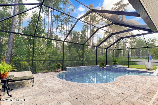 view of pool featuring a patio, glass enclosure, and an in ground hot tub